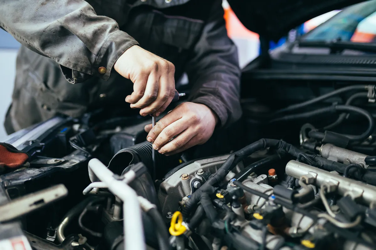 Kfz-Sachverständigenbüro Patrick Kunkel Wiesthal – Kfz-Mechaniker bei der Reparatur eines Autos. Selektiver Fokus.